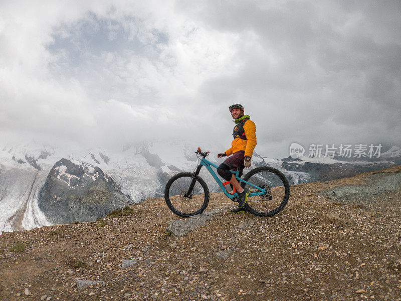男性山地自行车爱好者欣赏风景，土路，远处的冰川