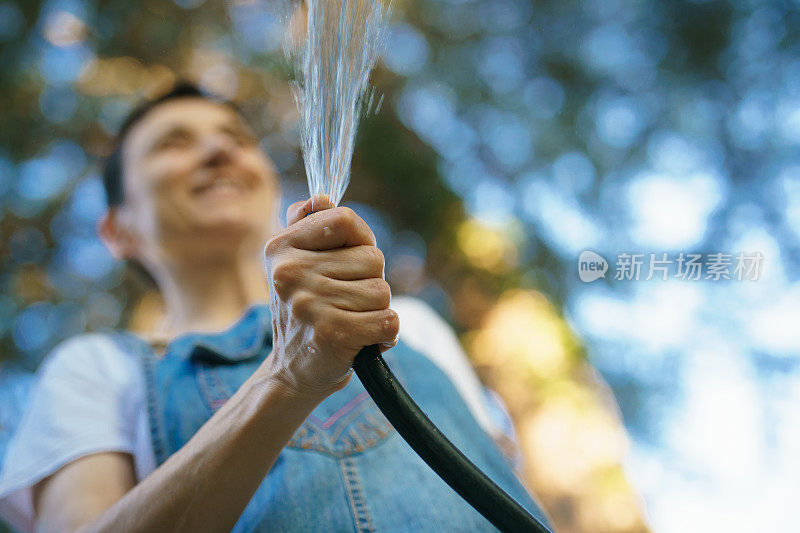 接近人类的手用软管浇灌花园