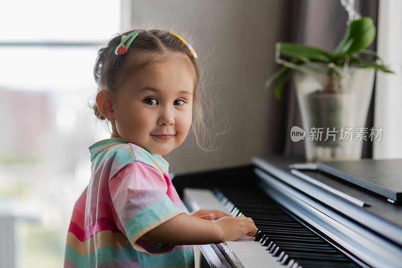 美丽的亚洲小女孩的肖像弹钢琴。