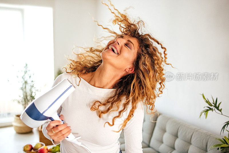 女人在吹头发的时候玩得很开心