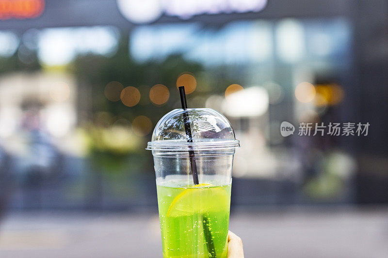 用塑料杯盛着柠檬水的女人的手