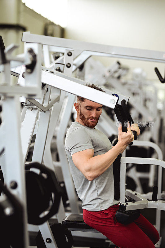 侧视图的人在健身机上工作在健身房。
