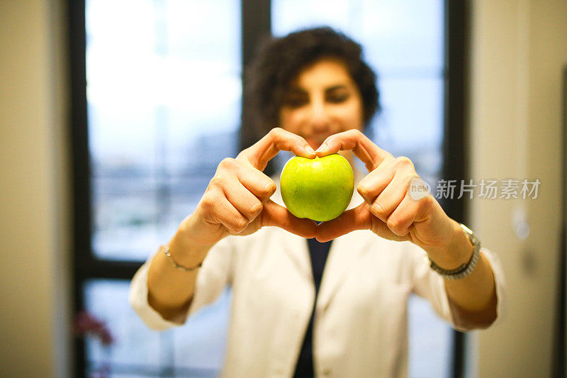 健康营养师在办公室拿着心形的苹果。健康饮食理念。减肥