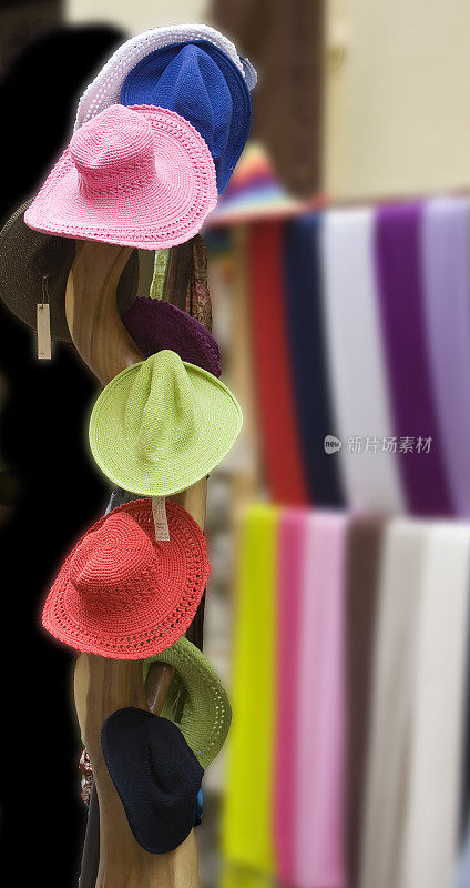 五颜六色的帽子和围巾，在街上零售展示。