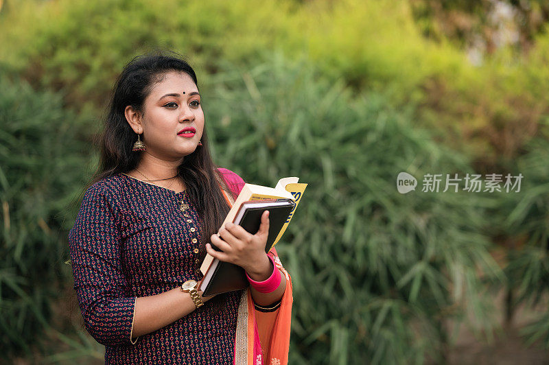 年轻的印度女大学生拿着书