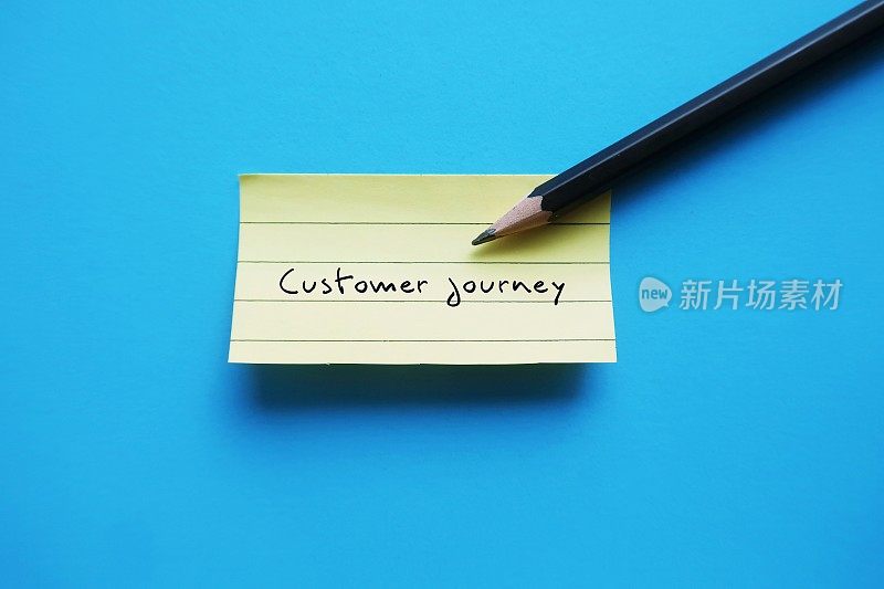 在蓝色背景上用铅笔写的便签“顾客之旅”——营销流行语，你的顾客在购买之前和之后采取的行动