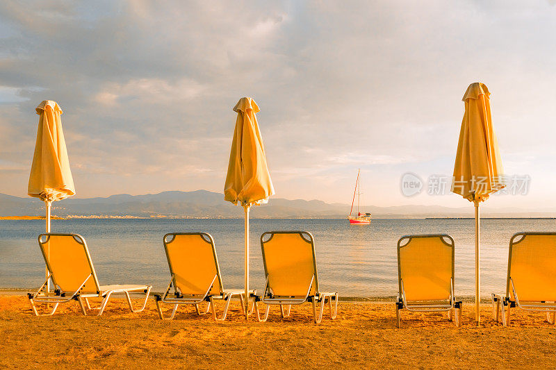 空沙滩椅伞太阳甲板椅沙滩躺椅海上游艇海滩帆船海岸日落帆船。海滨背景度假海上旅游太阳遮阳伞和躺椅，躺椅