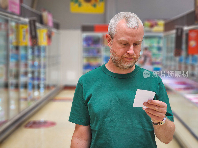 一名男子在超市过道检查购物清单