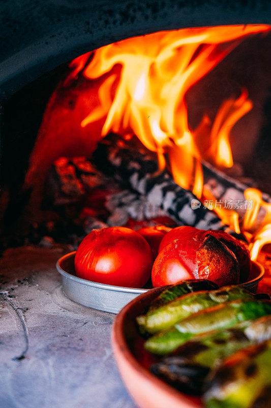在传统的石头烤箱里煮胡椒和西红柿