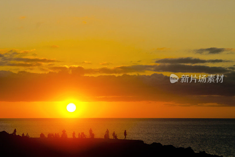 兰萨罗特岛海岸线，日落，火山岩景观，人群轮廓。