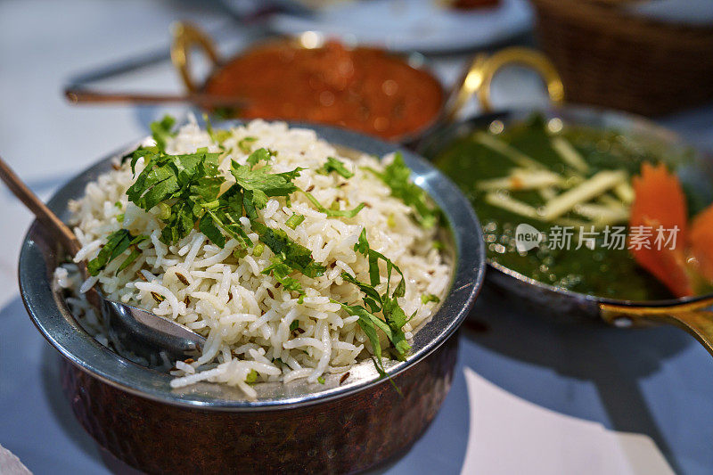 餐桌上摆满了印度菜，包括印度香饭、咖喱鸡和帕拉克奶酪。