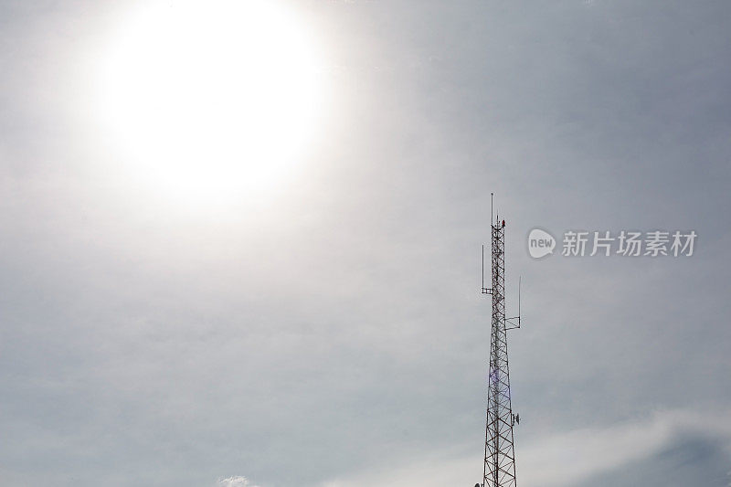 无线电发射塔在背光天空中以太阳为背景的无线电发射塔或电话发射塔