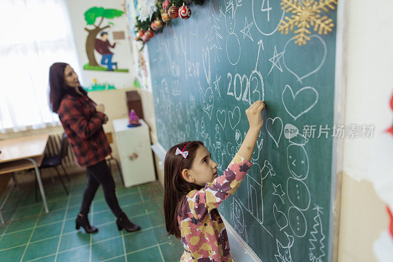 学校老师和学生在学校黑板上画圣诞装饰品