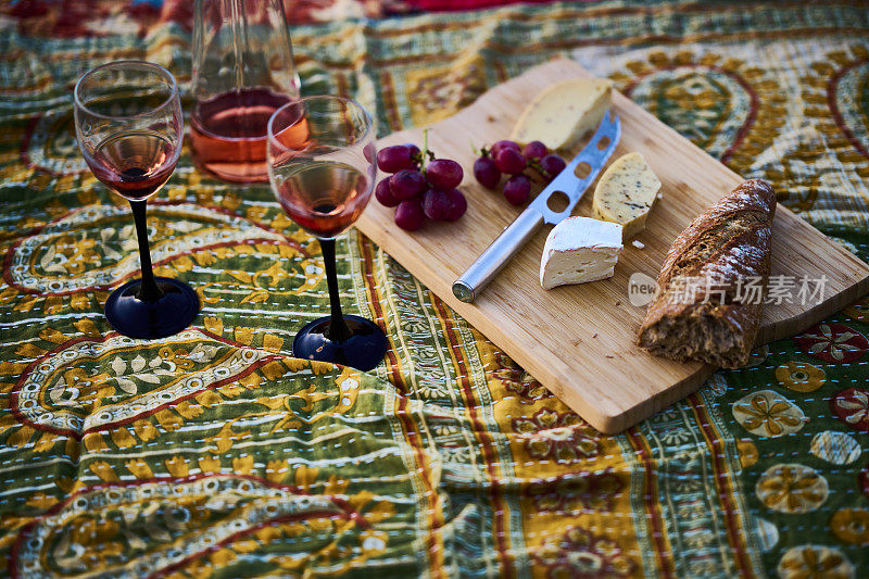 面包，酒和奶酪放在野餐毯上