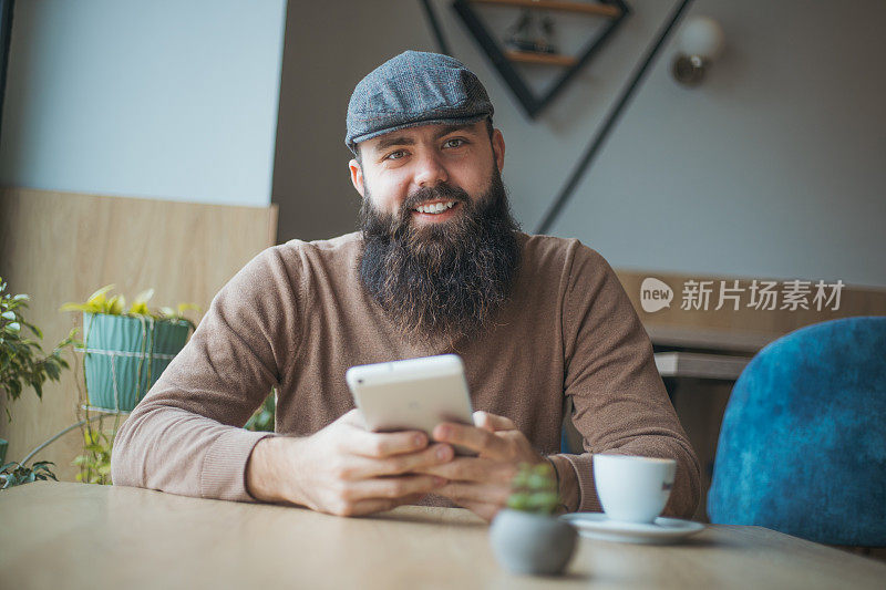 一个年轻人在咖啡馆里一边喝咖啡一边使用数码平板电脑