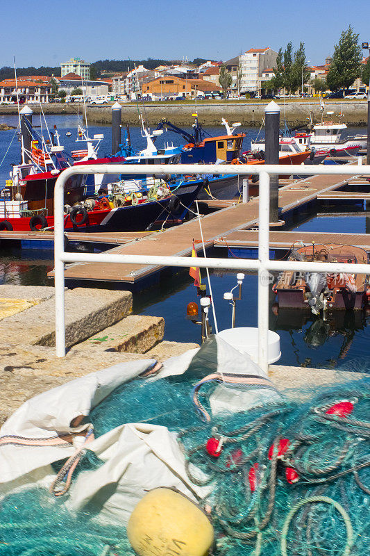 成堆的渔网，背景是停泊在港口的船只。