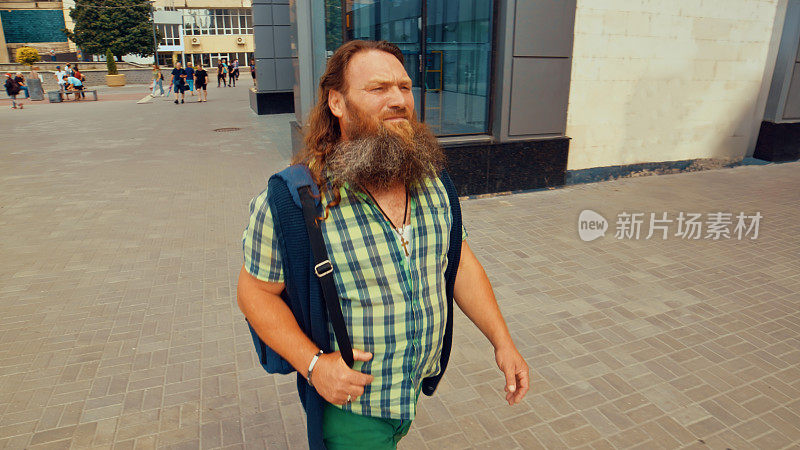 一位年长的长胡子男子在城市中穿行时，目不转睛地看着远处