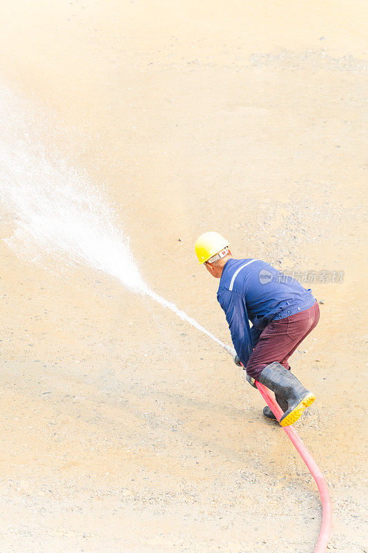 一个人在用水管清洁地面