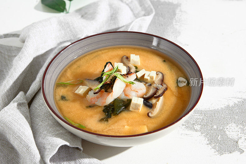 传统的味噌汤，虾，豆腐，蘑菇，用大葱装饰在一个石器碗里