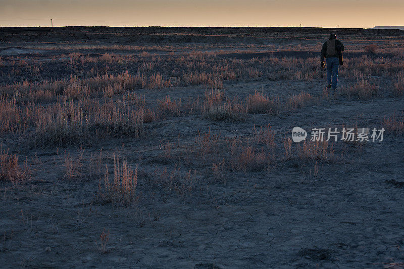 日落时分，一名男子在沙漠荒野中徒步旅行