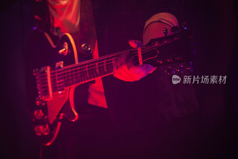 红色灯光下的舞台上有吉他手