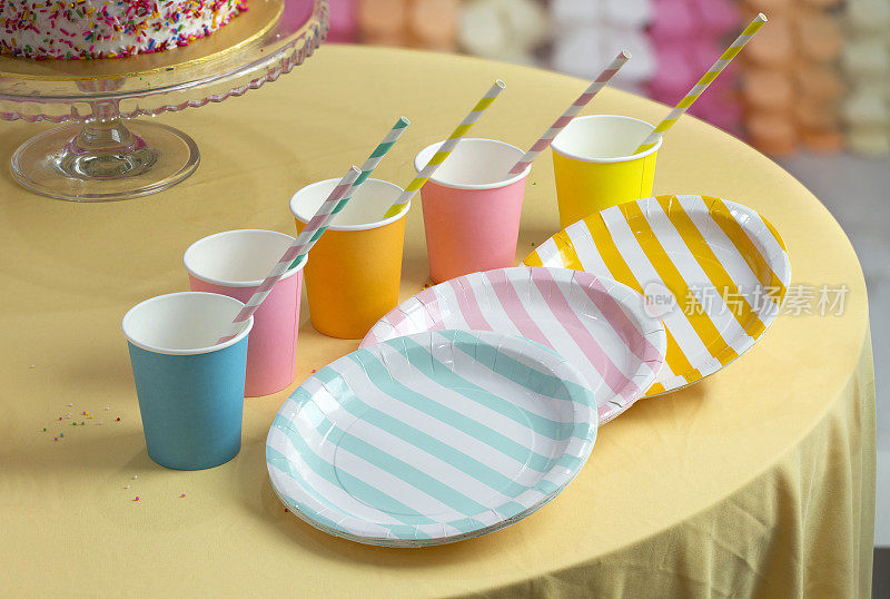 桌上放着五颜六色的派对纸杯和盘子。
