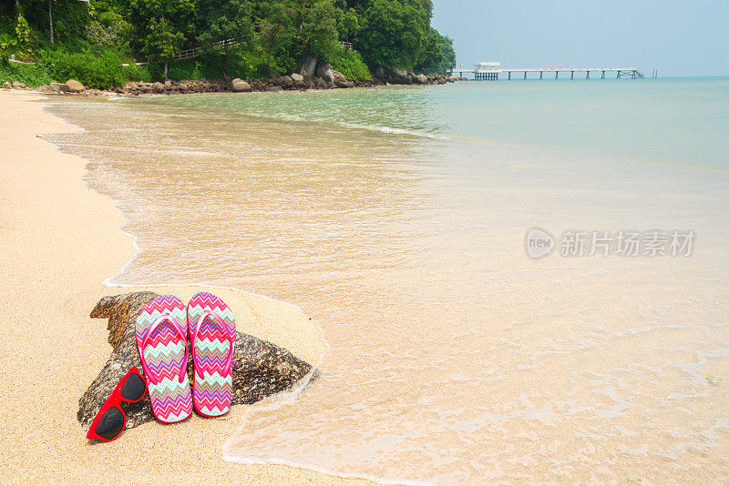 热带海滩上的彩色人字拖和太阳镜
