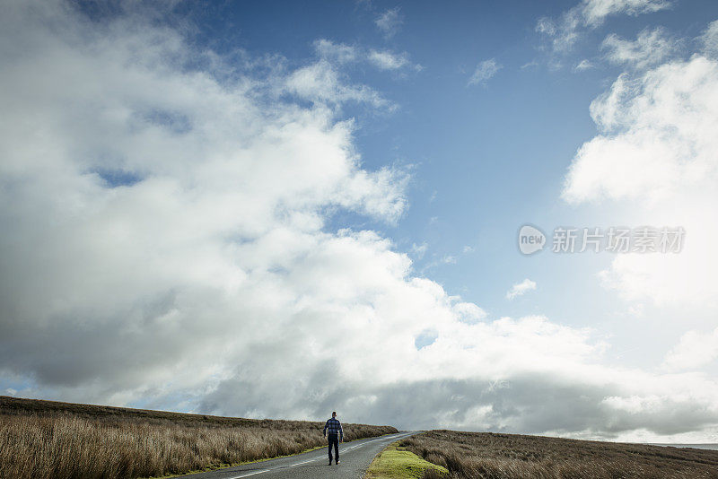 一个人走在开阔的乡村道路上