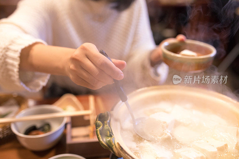 年轻女子从火锅里捡豆腐