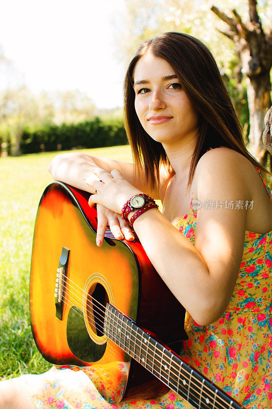 一个十几岁的女孩在公园里拿着吉他的肖像