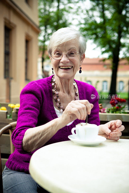 路边咖啡馆里露齿微笑的老妇人