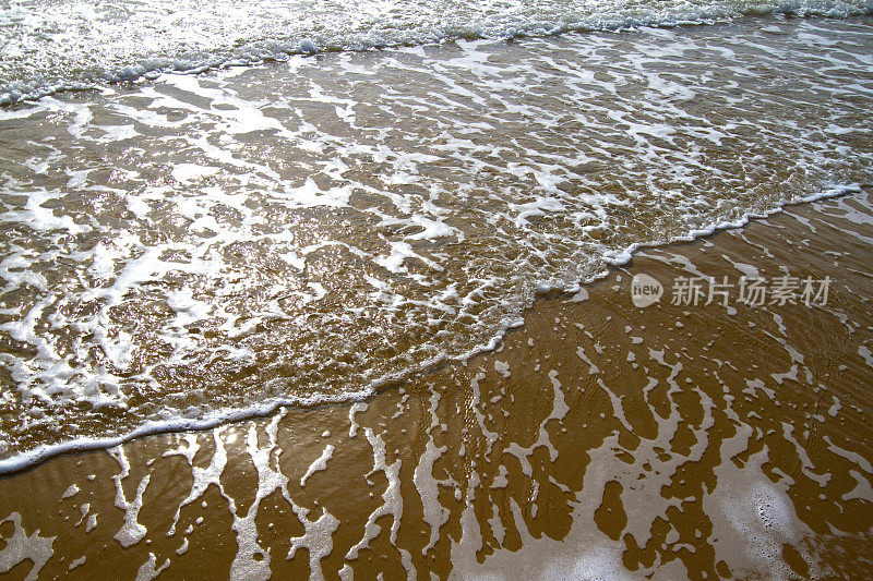 宁静:柔和的海浪，阳光反射在金色的沙滩上