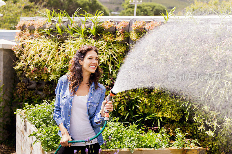 在苗圃里给植物浇水的快乐女人