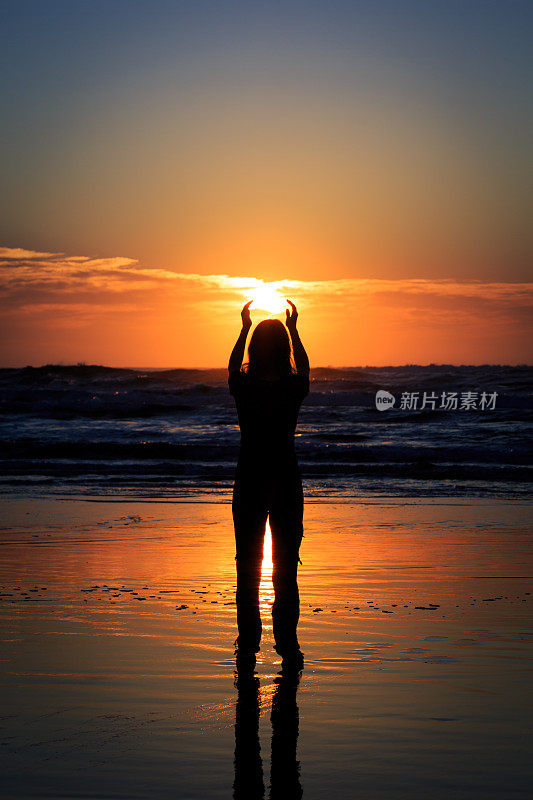 日出时，在热带海滩上的女人剪影