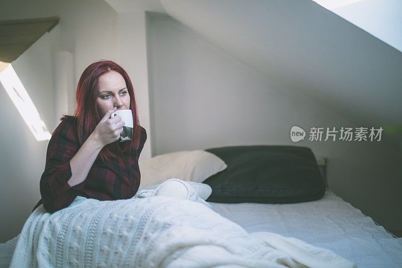 年轻女子在床上悠闲地喝着茶