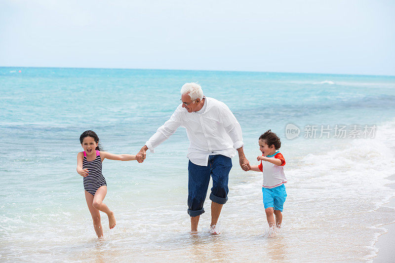 爷爷和他的孙子们在海滩上玩