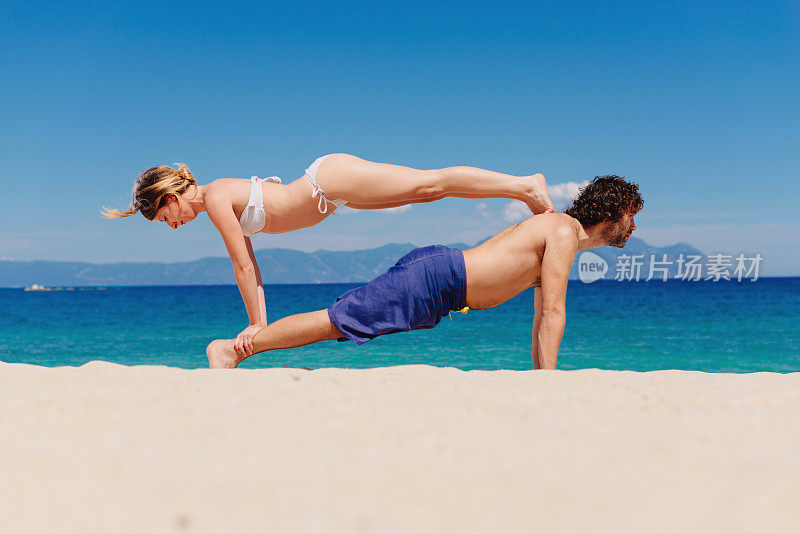 一对情侣在海边的沙滩上练习瑜伽