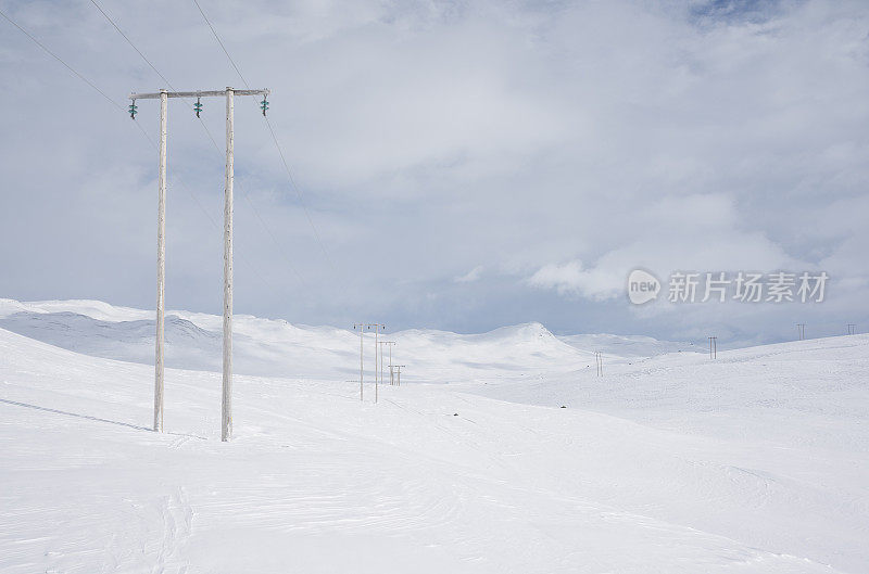 冬季山区的木制塔架和高压电缆