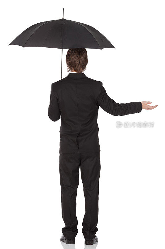 一个商人站在伞下的后视图