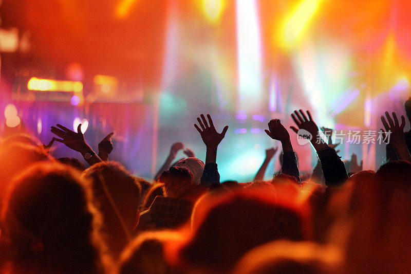 青少年在音乐会上举起双手，点亮舞台灯光