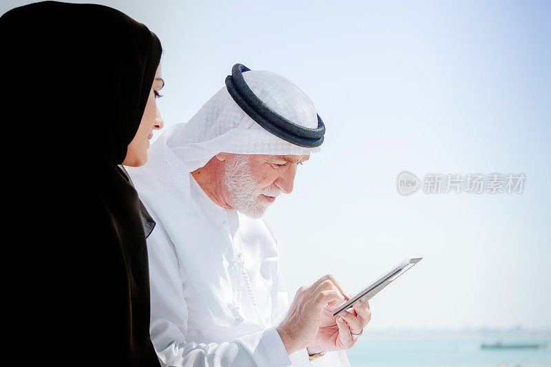 阿拉伯老人和年轻妇女享受智能手机。