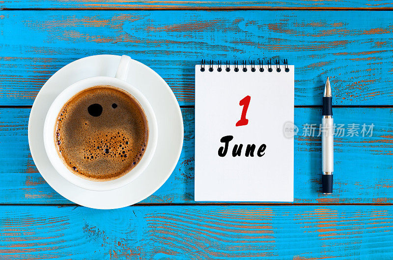 6月1日。月1日，每天的日历与早上的咖啡杯在蓝色的木制背景。夏季概念，俯视图