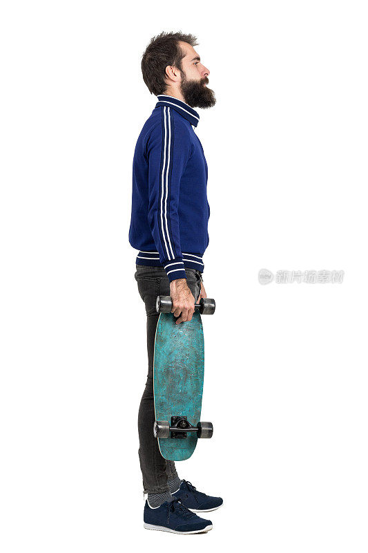 侧面的年轻潮人在运动夹克携带滑板