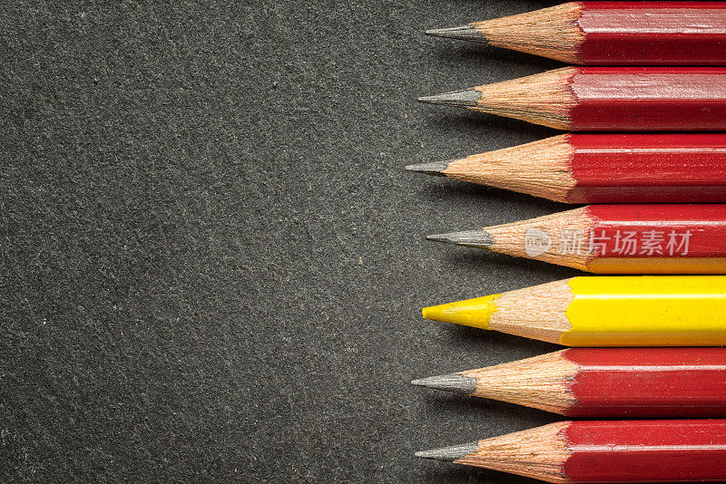 黄色铅笔从一群一模一样的黑家伙中脱颖而出。领导力、独特性、独立性、主动性、战略、异议、异思、商业成功理念。