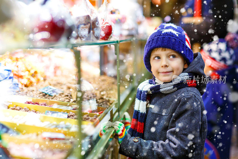 一个小男孩在圣诞市场上吃着苹果糖