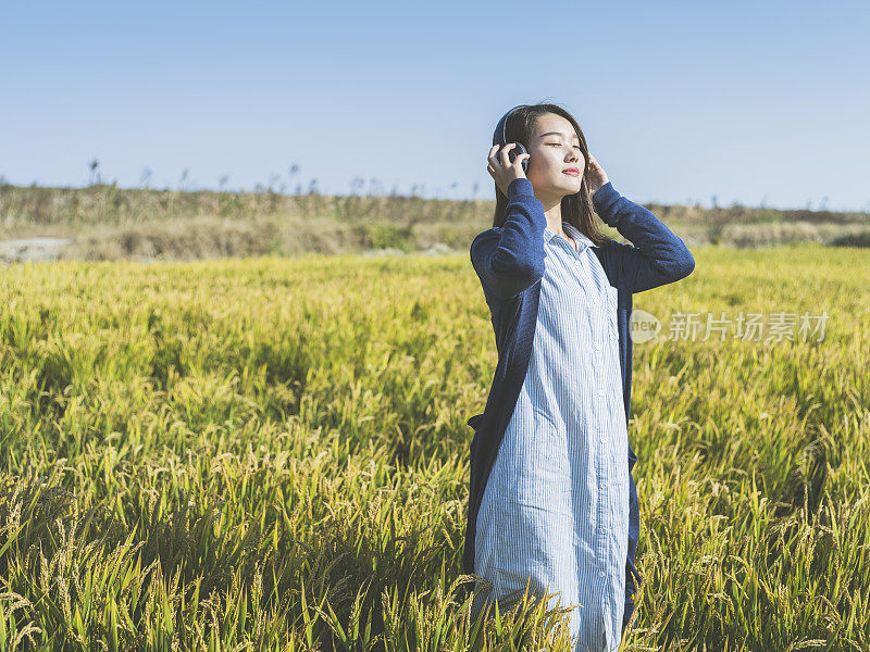 年轻女孩戴着耳机在野外