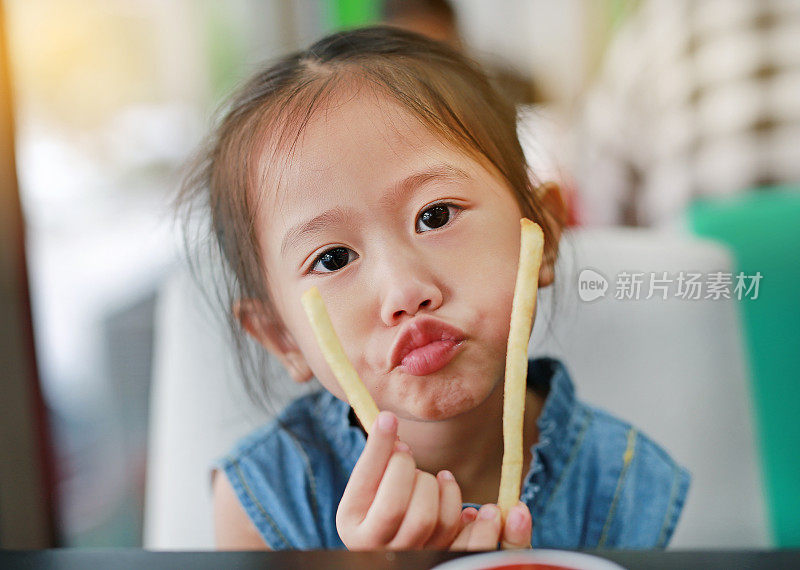 可爱的亚洲女孩吃薯条。