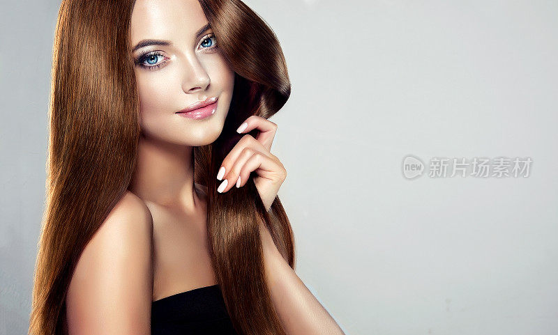 年轻，棕色头发美丽的模特，长，直，整齐的头发是温柔地触摸自己的头发。