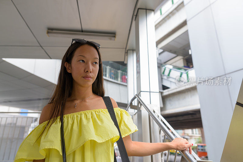 年轻美丽的多民族旅游妇女肖像在商场外的城市曼谷泰国