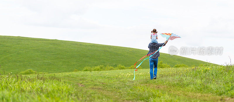 幸福的家庭父亲和小女儿在草地上追风筝